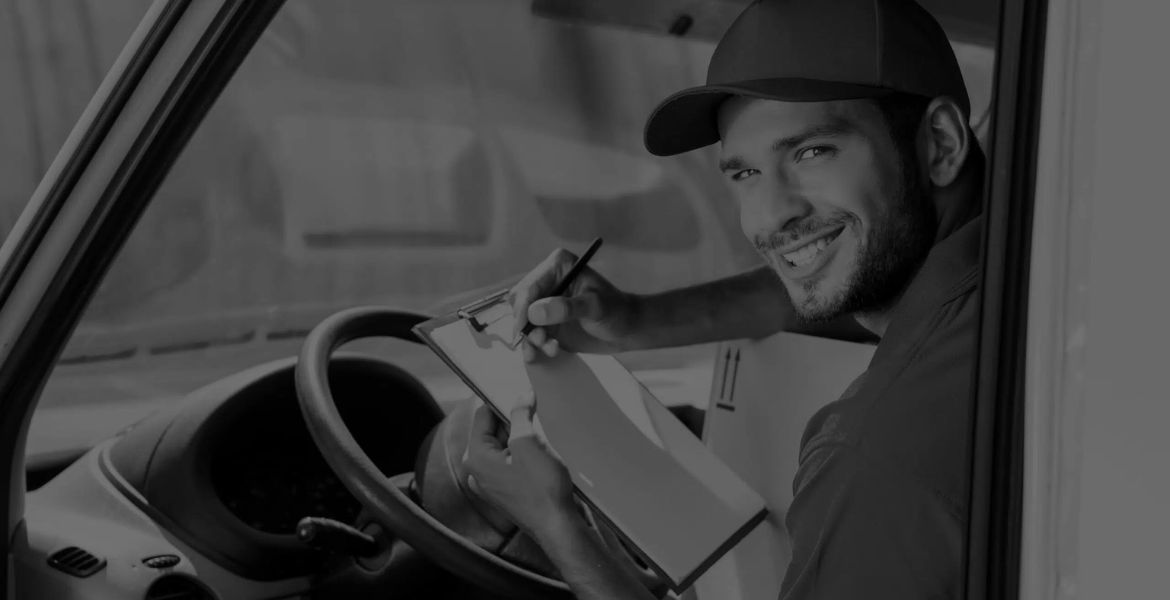 Livreur Deliver-e souriant au volant de sa camionnette